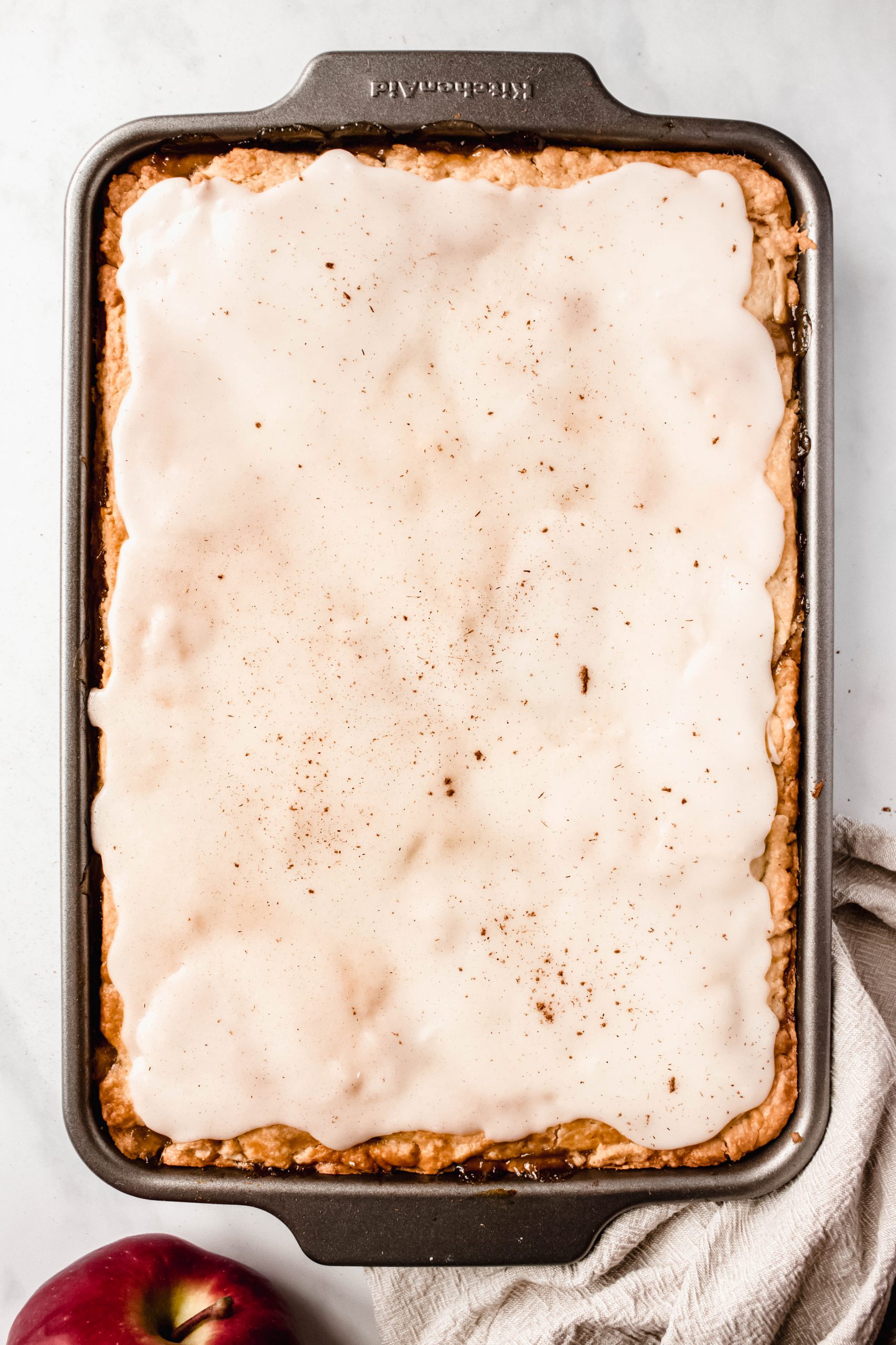 Sheet pan apple pie after baking with icing poured.