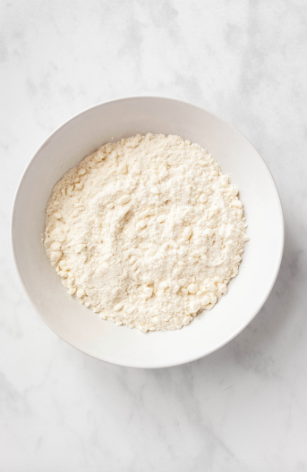 Flour, sugar, salt, and pea-sized butter bits in a bowl.