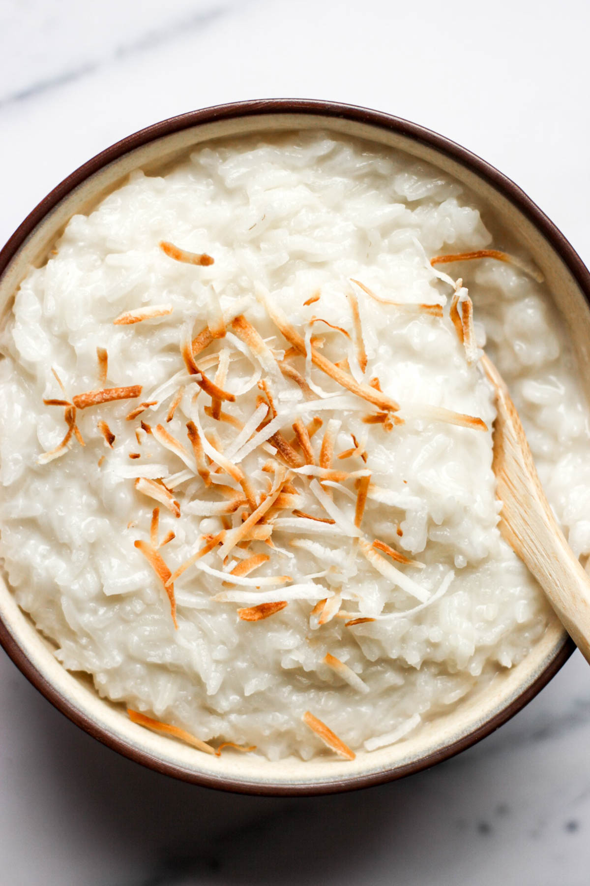 bowl of freshly made coconut rice pudding topped with toasted coconut flakes