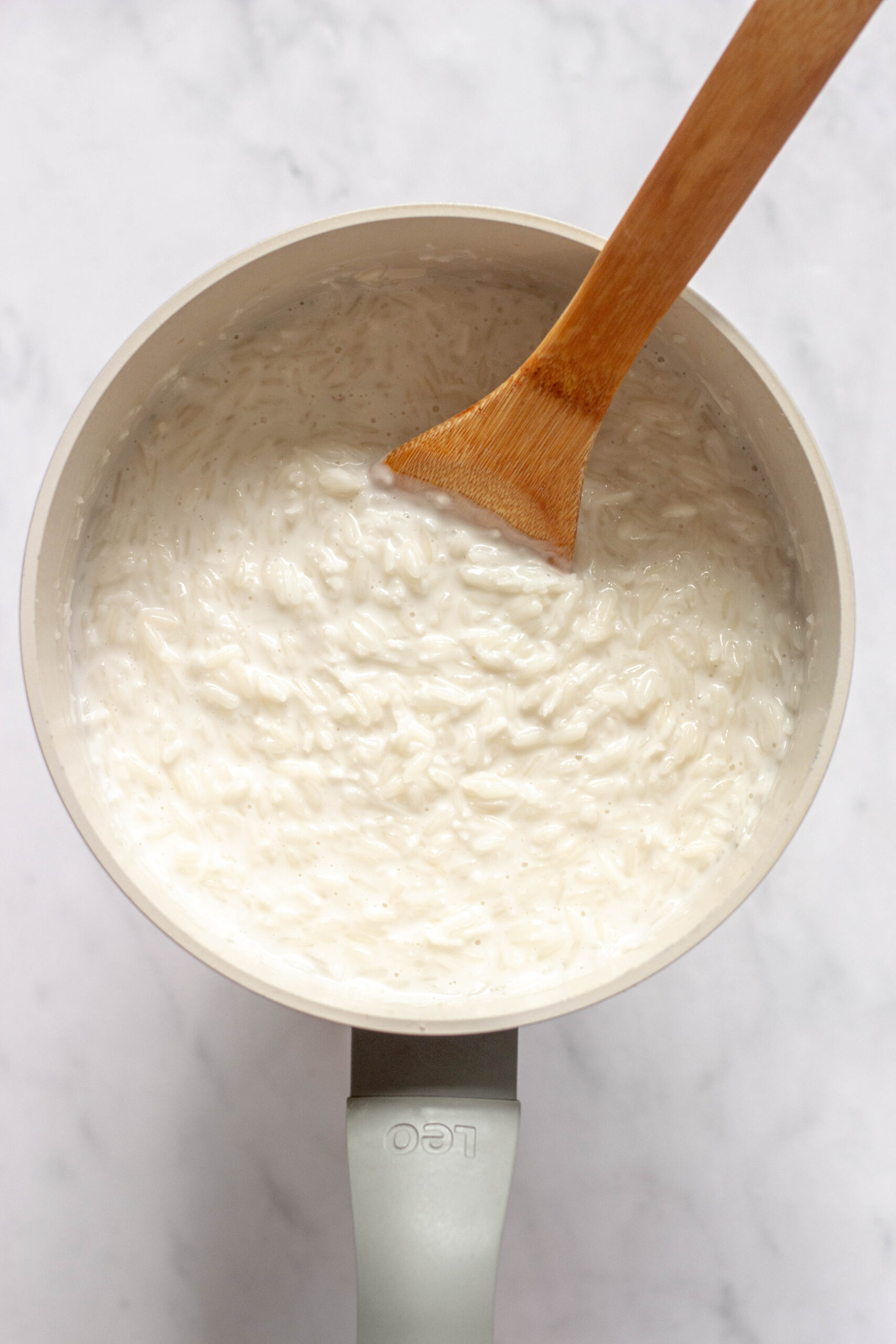 freshly made coconut rice pudding stirred with a wooden spoon in a saucepan