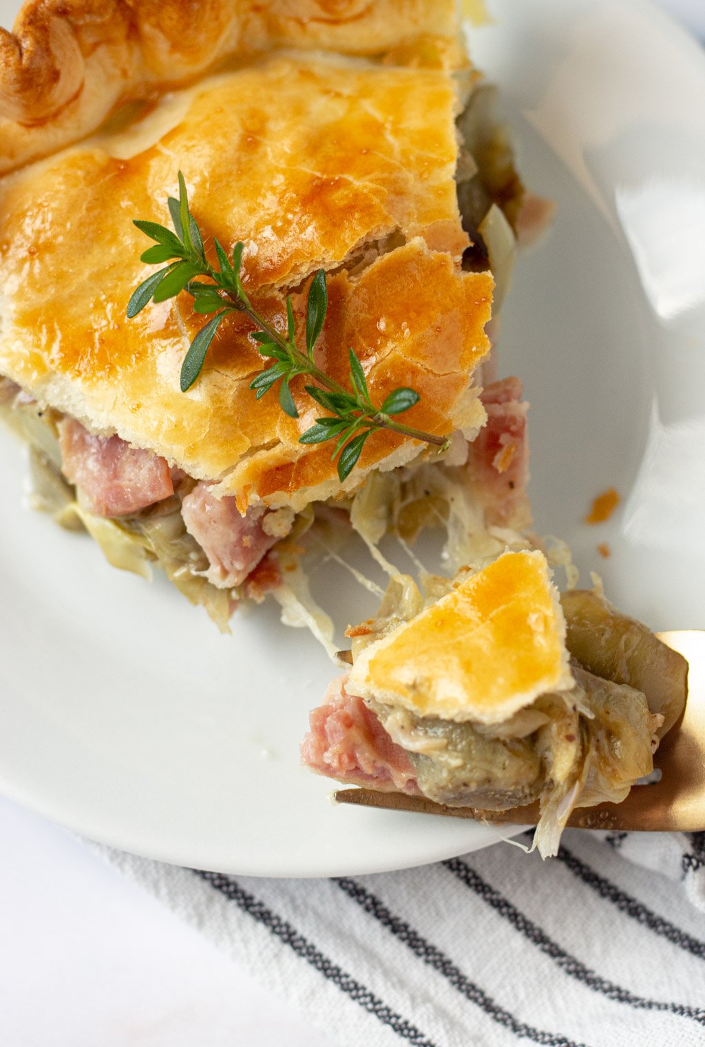 slice of artichoke pie with cheese pull on a white dish