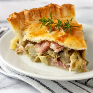 slice of ham and cheese artichoke pie on a white plate