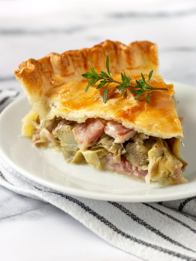 slice of ham and cheese artichoke pie on a white plate