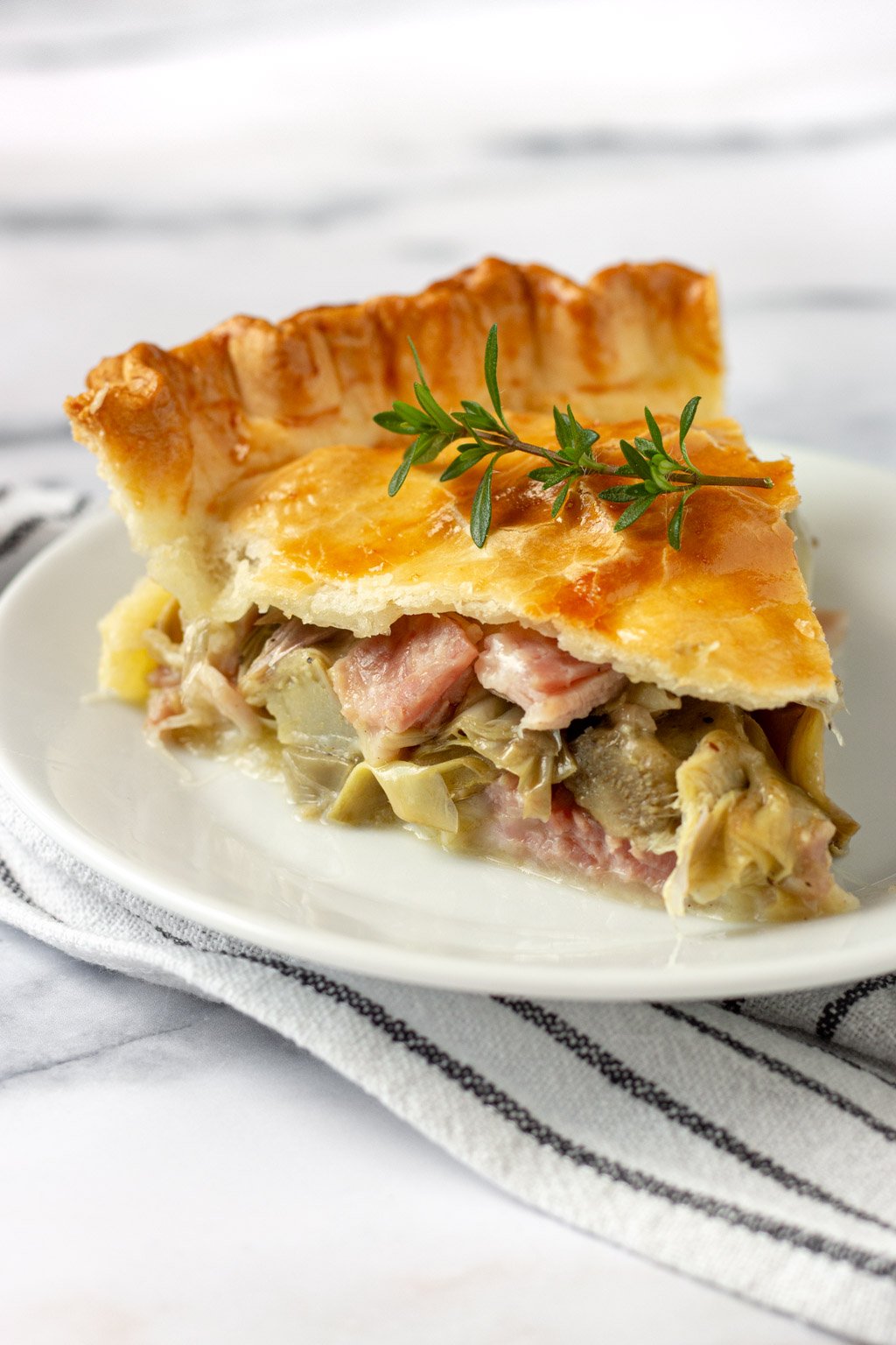 slice of ham and cheese artichoke pie on a white plate