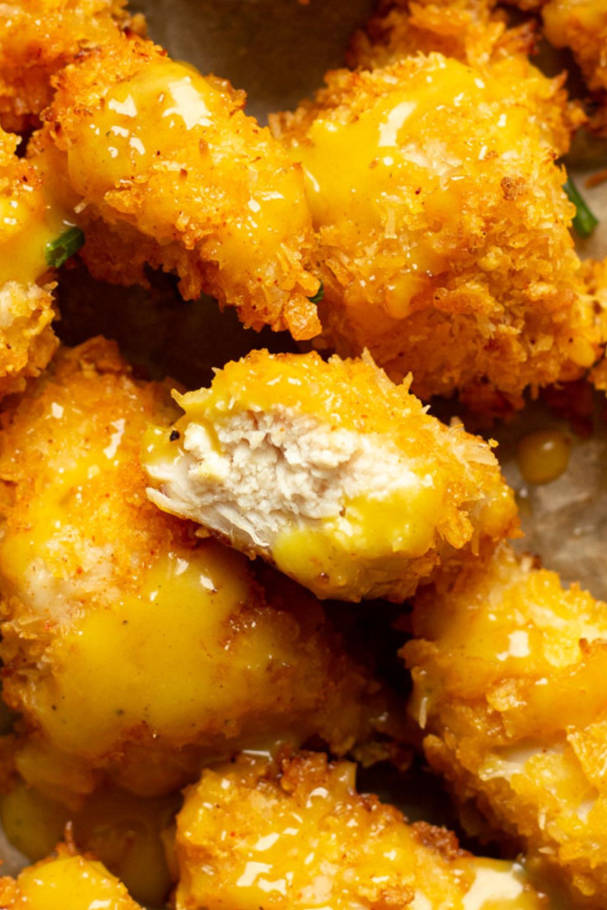 Crispy oven-fried popcorn chicken with one piece bitten open to show the juicy, tender interior