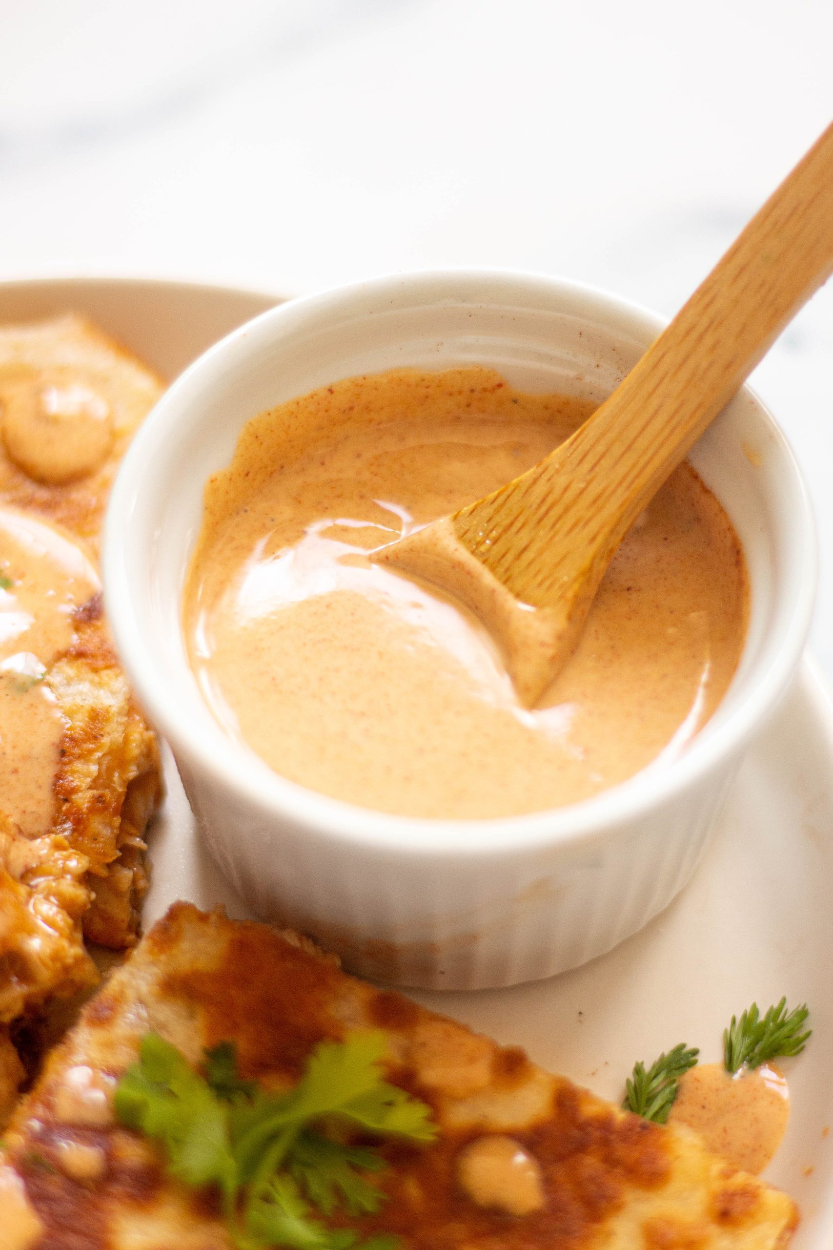 small ramekin filled with creamy chicken quesadilla sauce being stirred with a small wooden spoon.